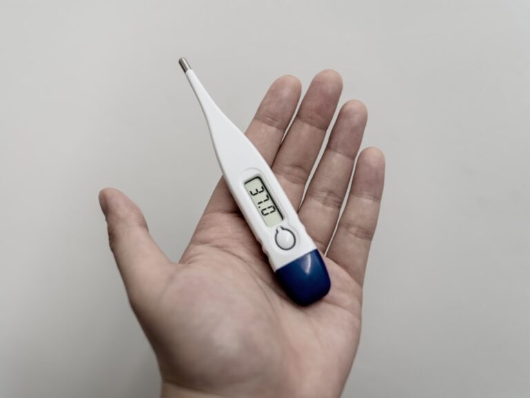 Person checking body temperature while monitoring respiratory symptoms